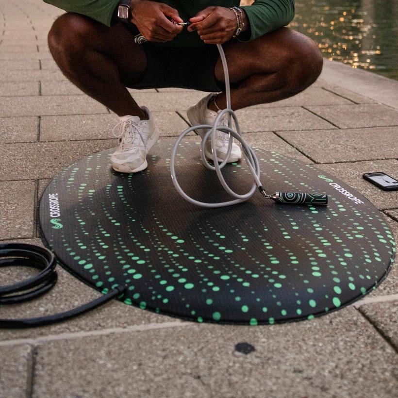 Jump Rope Mat (Flow) Person standing on the new Crossrope Jump Rope Mat clipping a handle into a weighted jump rope.