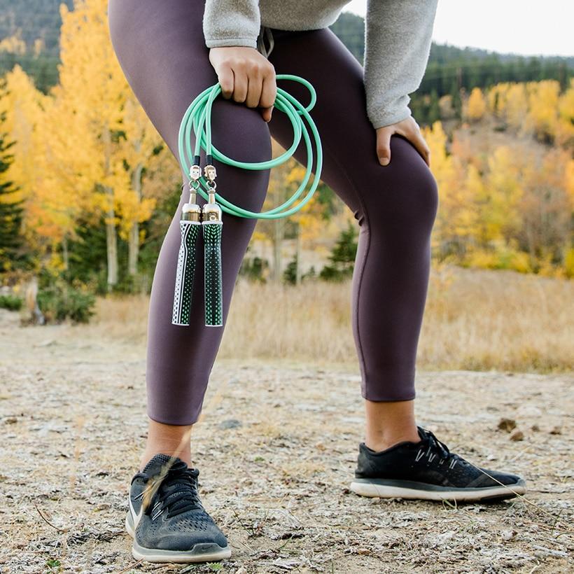 Starter Jump Rope Set Woman outside in running shoes holding 1/4 LB ropes with Slim handles